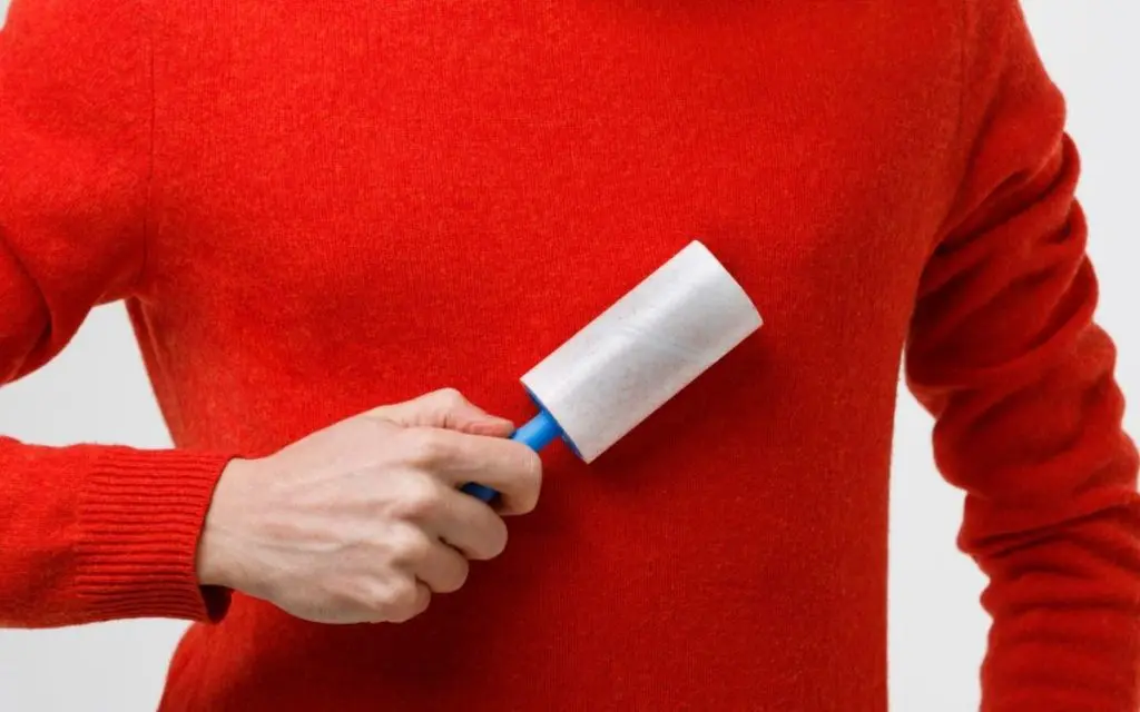 Man Using a lint remover on red shirt