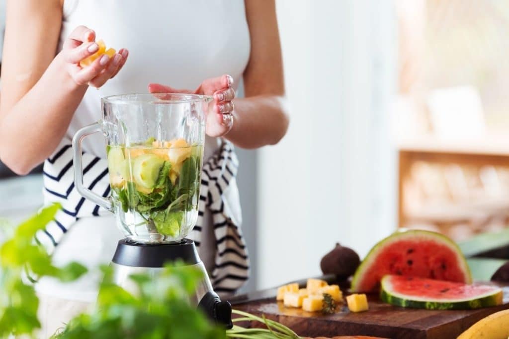 Woman using blender to make an energizing drink Food processors vs blenders