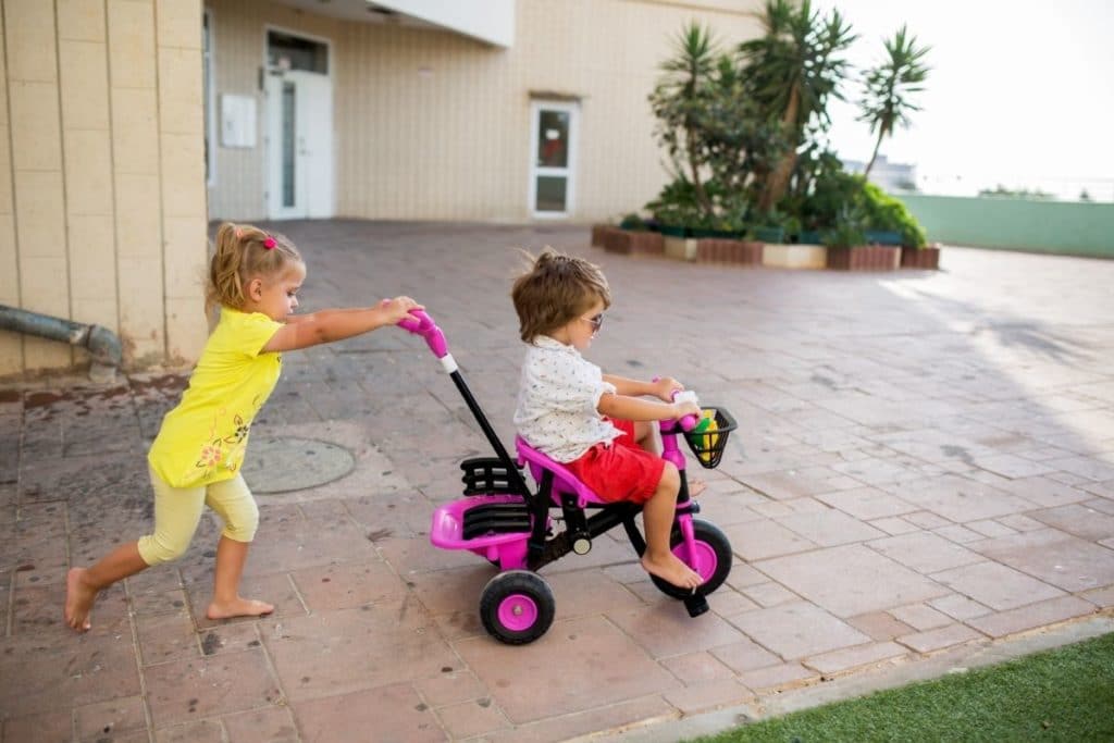 Two kids playing with one of the best Tricycles with Push Handles